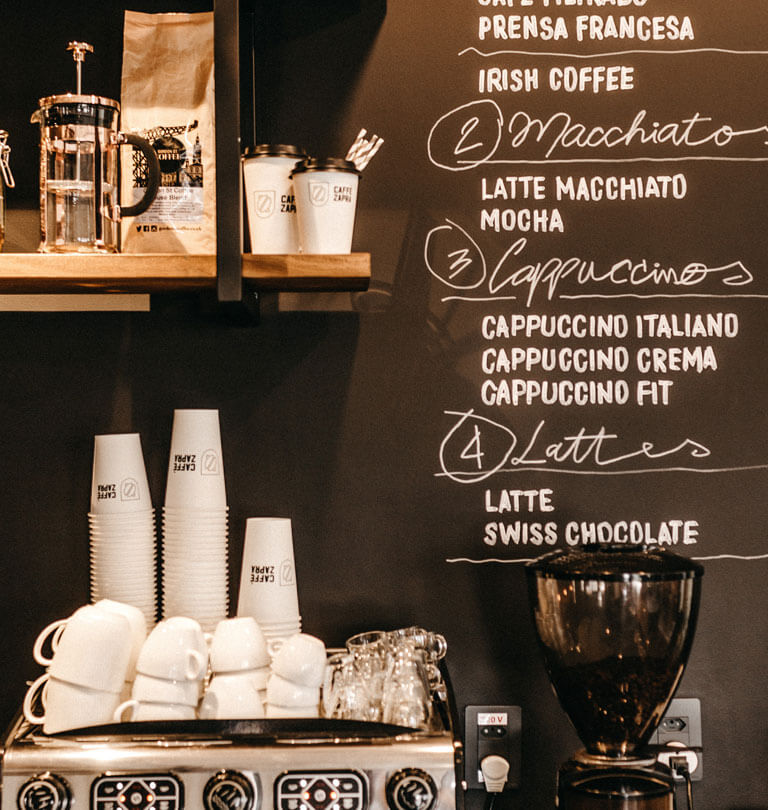 manual coffee machine in front of a chalk board coffee menu