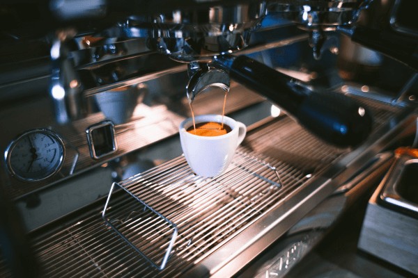 An espresso being poured from a manual espresso coffee machine.